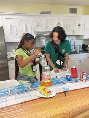 Volunteer assists camper in kitchen